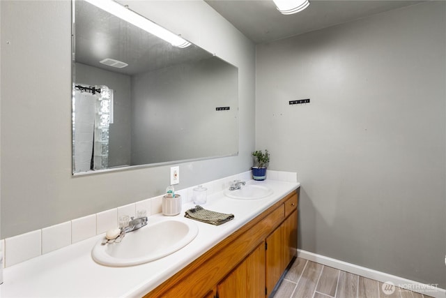 bathroom featuring double vanity, a sink, baseboards, and wood finished floors