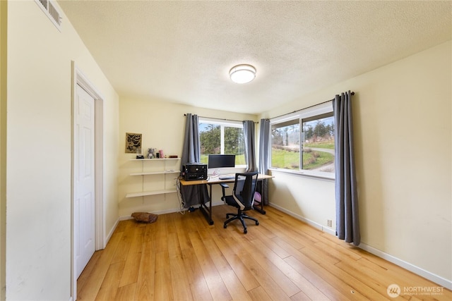 office area featuring visible vents, a textured ceiling, hardwood / wood-style flooring, and baseboards