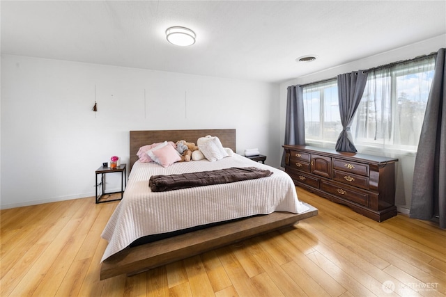 bedroom with light wood-style flooring, visible vents, and baseboards