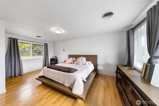 bedroom featuring light wood-style flooring, visible vents, and baseboards