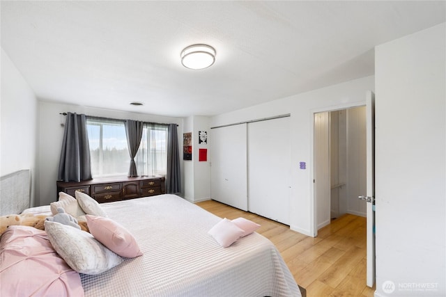 bedroom with light wood finished floors, a closet, and baseboards