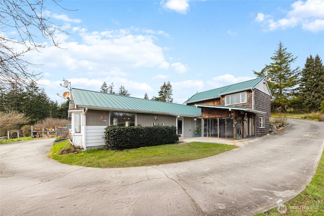 view of front of home featuring metal roof, a front lawn, and driveway