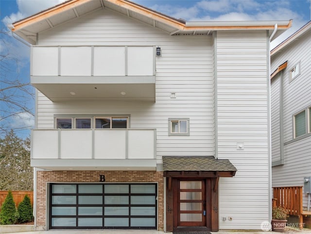 view of front of home featuring brick siding, a balcony, and an attached garage