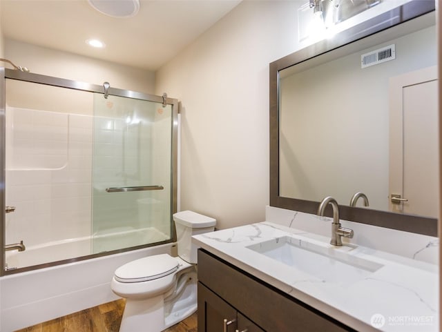 bathroom with enclosed tub / shower combo, toilet, wood finished floors, vanity, and visible vents