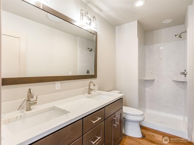 full bathroom with wood finished floors, walk in shower, a sink, and toilet