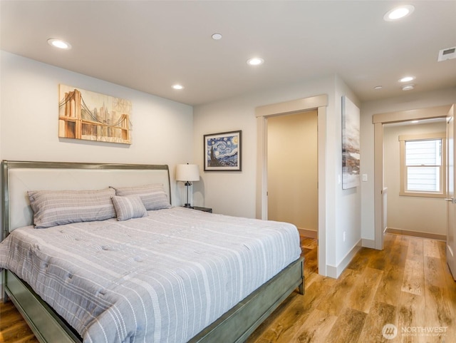 bedroom featuring visible vents, baseboards, wood finished floors, and recessed lighting