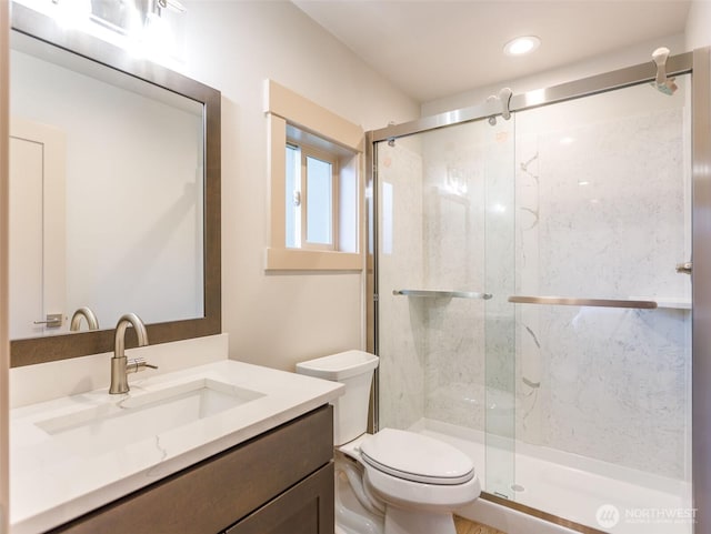 bathroom featuring toilet, a marble finish shower, and vanity