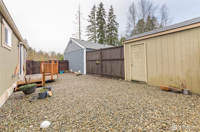 view of yard featuring a fenced backyard, a shed, a wooden deck, and an outdoor structure