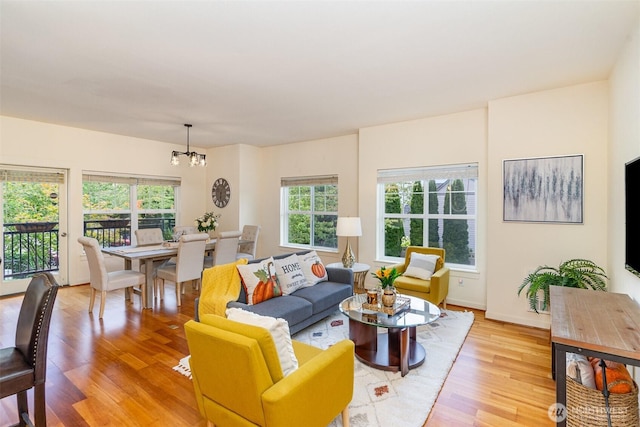 living room featuring a healthy amount of sunlight, light wood-style floors, and a chandelier