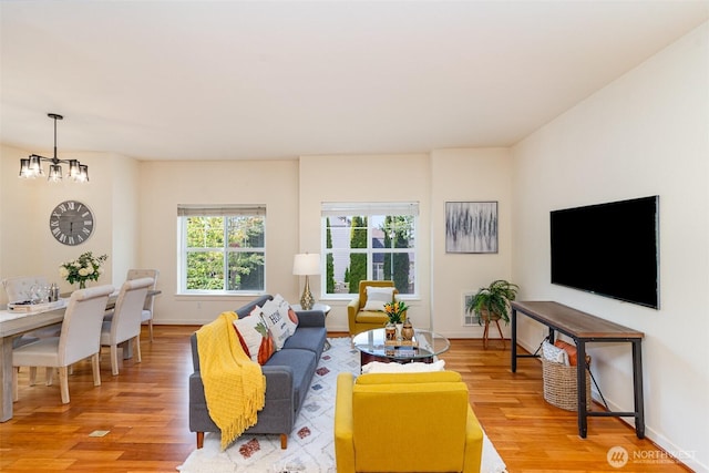 living room featuring baseboards, an inviting chandelier, and wood finished floors