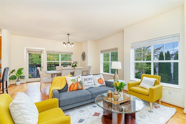 living room with light wood-style floors, a notable chandelier, and baseboards