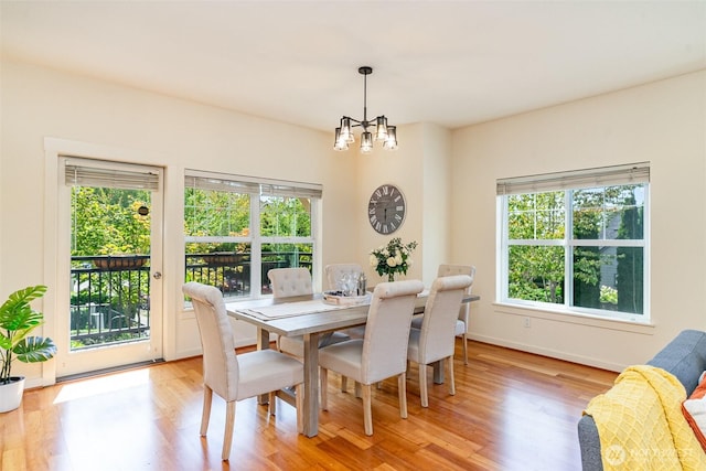 dining area with light wood-style floors, a notable chandelier, and baseboards