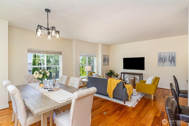 dining room with a healthy amount of sunlight, an inviting chandelier, and wood finished floors