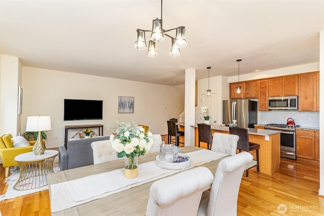 dining space featuring light wood finished floors and an inviting chandelier