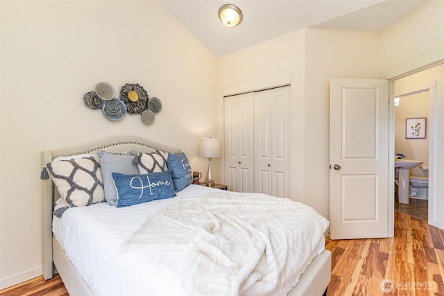 bedroom featuring lofted ceiling, a closet, baseboards, and light wood finished floors