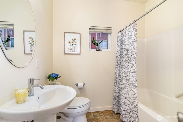 bathroom with toilet, shower / bath combo with shower curtain, a sink, baseboards, and tile patterned floors