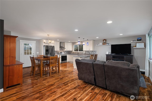 living room with baseboards, dark wood-type flooring, an inviting chandelier, and recessed lighting