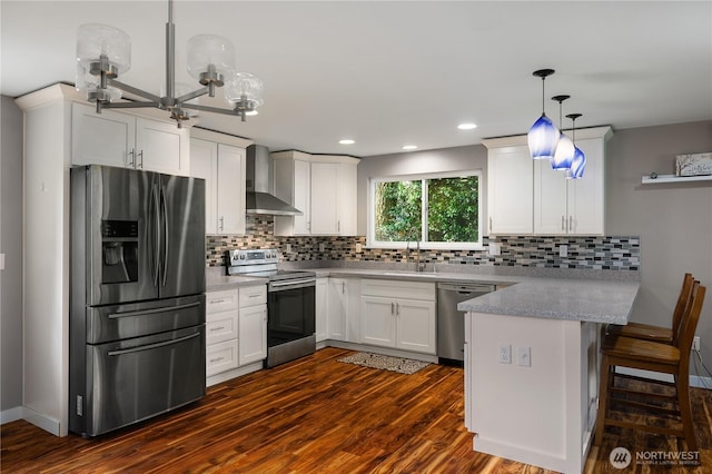 kitchen featuring decorative backsplash, appliances with stainless steel finishes, dark wood-type flooring, a peninsula, and wall chimney exhaust hood