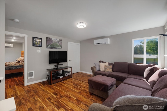 living area featuring a wall mounted air conditioner, wood finished floors, visible vents, and baseboards