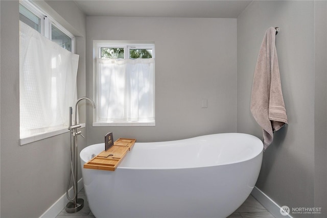 bathroom featuring a soaking tub and baseboards