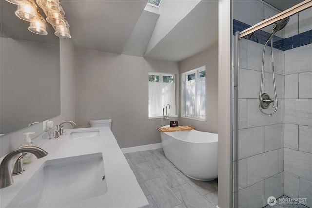 full bath featuring a shower stall, a freestanding bath, baseboards, and a sink