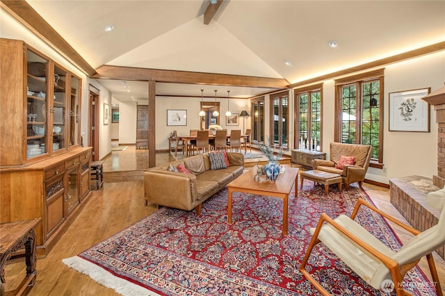 living room with a brick fireplace, light wood-style flooring, high vaulted ceiling, and beamed ceiling