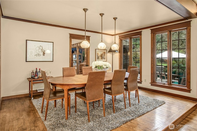 dining area featuring baseboards, hardwood / wood-style flooring, and crown molding