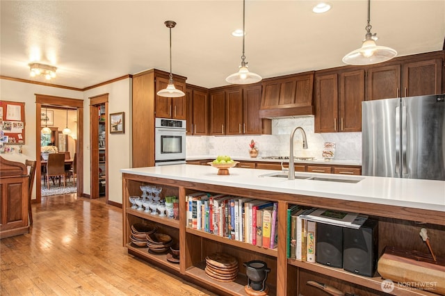 kitchen featuring light countertops, ornamental molding, light wood-type flooring, freestanding refrigerator, and tasteful backsplash