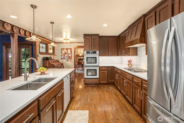 kitchen featuring a sink, light countertops, appliances with stainless steel finishes, backsplash, and wood-type flooring