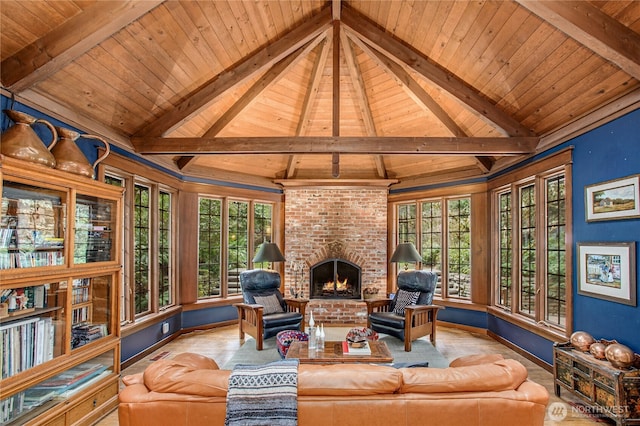 living room with vaulted ceiling with beams, plenty of natural light, baseboards, and a brick fireplace