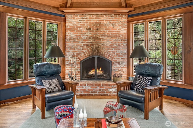 living area with a fireplace, baseboards, a wealth of natural light, and wood finished floors