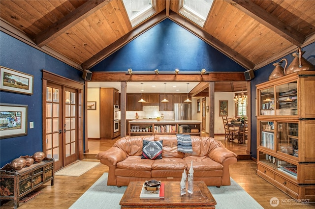 living area featuring wooden ceiling, light wood-style flooring, a skylight, french doors, and beamed ceiling