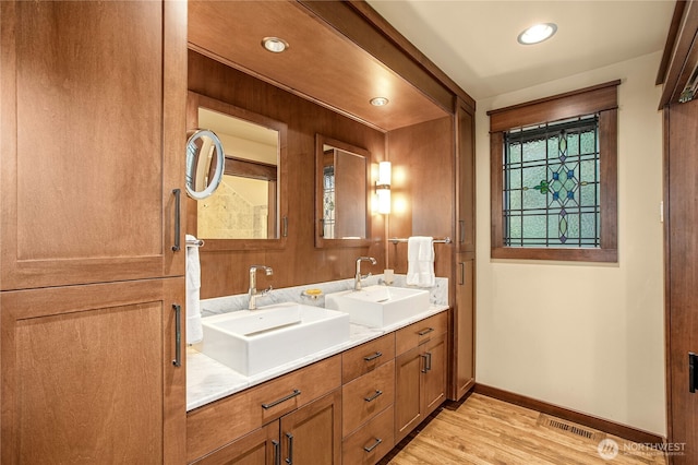 bathroom with double vanity, a sink, baseboards, and wood finished floors