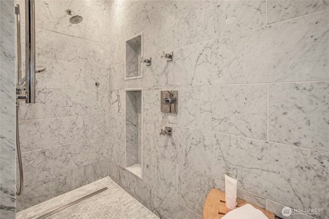 full bathroom featuring tiled shower and toilet