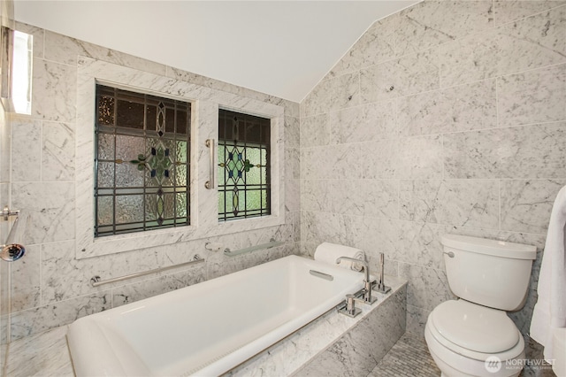 bathroom featuring vaulted ceiling, a garden tub, toilet, and tile walls