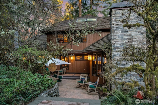 back of property at dusk featuring a patio area and a wooden deck