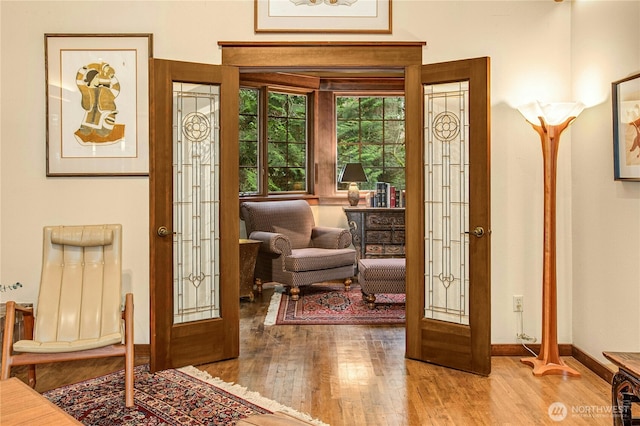 doorway to outside with baseboards, wood finished floors, and french doors