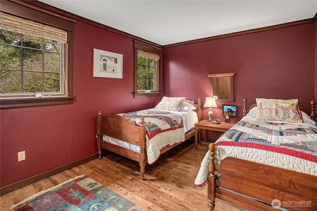 bedroom featuring baseboards, wood finished floors, and a textured wall