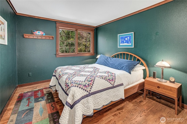 bedroom featuring ornamental molding, a textured wall, and wood finished floors