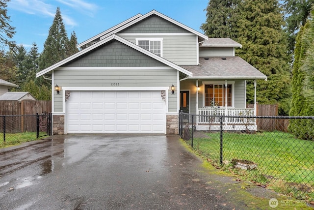 view of front facade featuring driveway, stone siding, a fenced front yard, and a front lawn