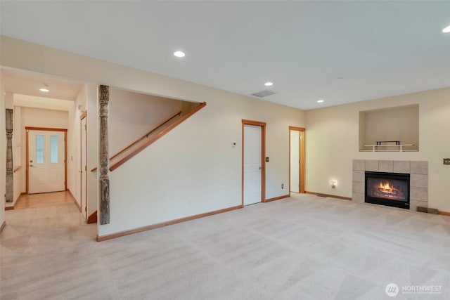 unfurnished living room with recessed lighting, visible vents, stairway, a tiled fireplace, and baseboards