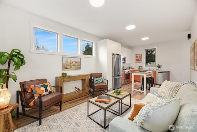 living area with light wood-style flooring and recessed lighting