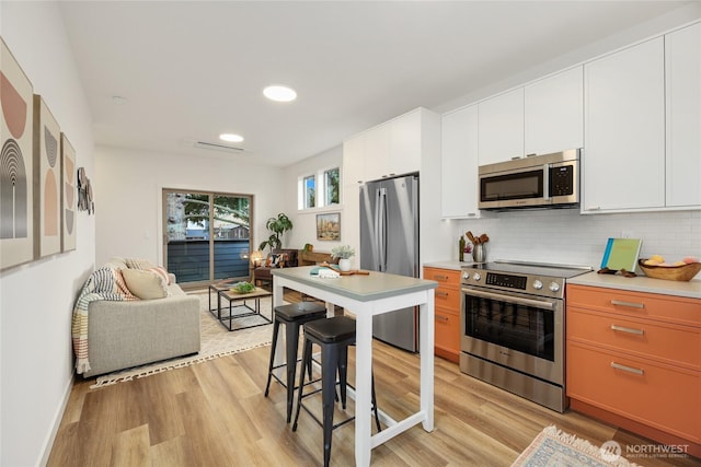 kitchen featuring decorative backsplash, appliances with stainless steel finishes, white cabinets, and light countertops