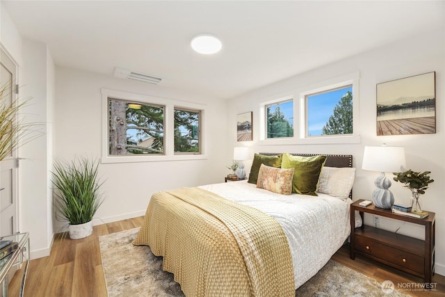 bedroom with visible vents, light wood-style flooring, and baseboards