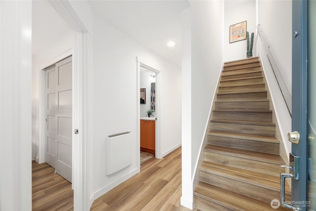 staircase with baseboards, wood finished floors, and recessed lighting