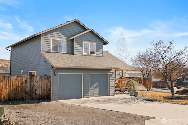 view of front of home with driveway, a shingled roof, a garage, and fence