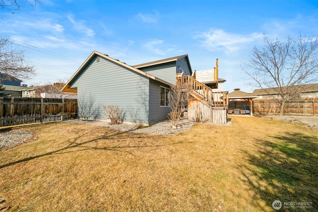 rear view of house featuring fence, stairway, a gazebo, and a lawn