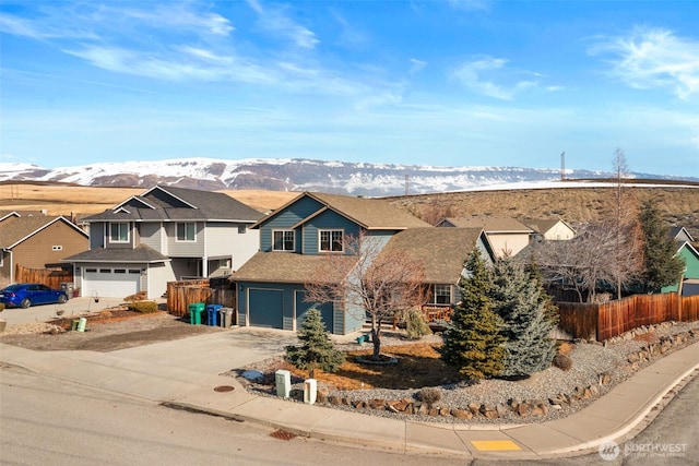 traditional-style house featuring driveway, a residential view, fence, and a mountain view