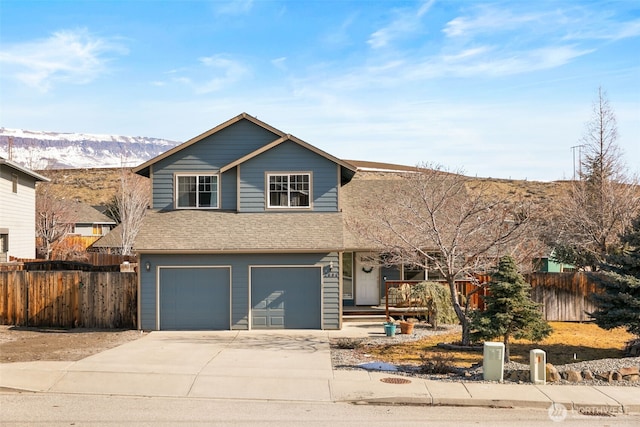 traditional-style house featuring a porch, concrete driveway, an attached garage, fence, and a mountain view