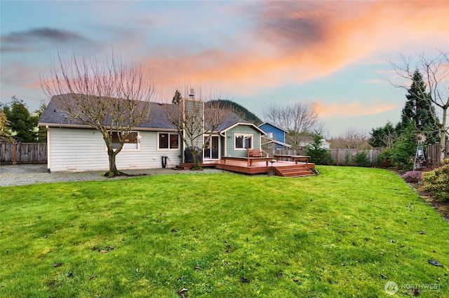 rear view of property with a fenced backyard, a deck, and a lawn